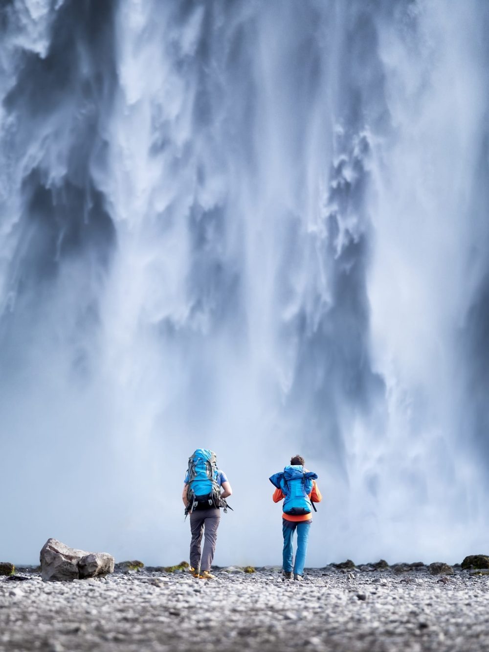 Iceland. Travelers couple look at the Skogafoss waterfall.